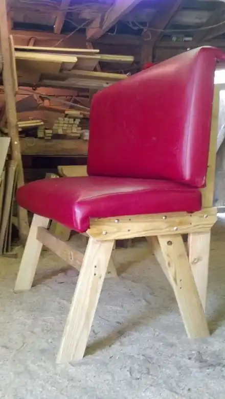 A chair with red vinyl upholstery, photographed inside the workshop