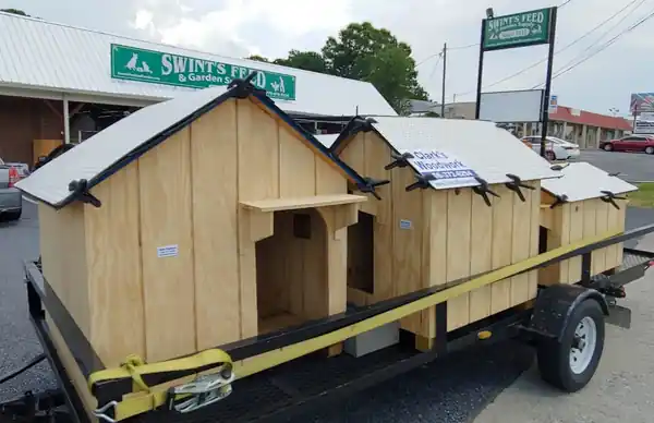 Pet houses strapped onto a flatbed trailer outside a feed and garden store