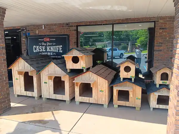 A lineup of Clark's Woodwork dog houses at a brick storefront