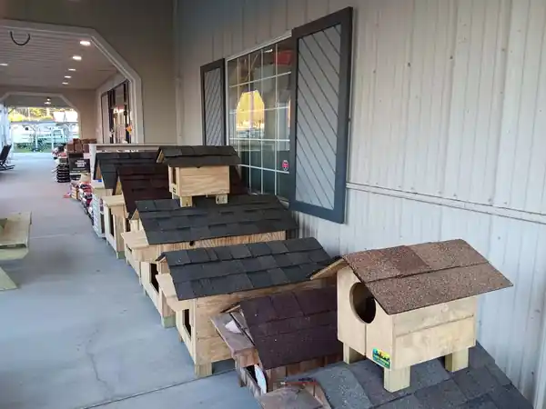 A long display of Clark's Woodwork pet houses under a covered walkway at a retailer