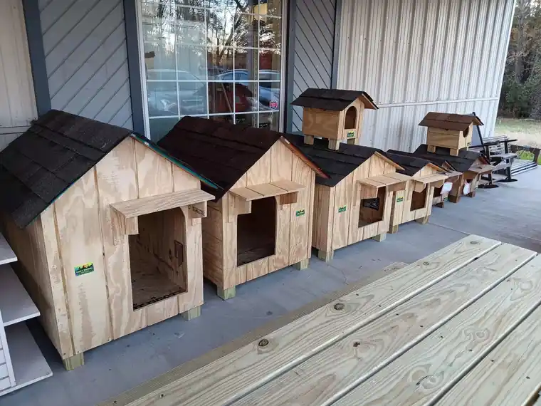 A graduated row of Clark's dog houses with dark shingle roofs on a dealer's porch, small to large