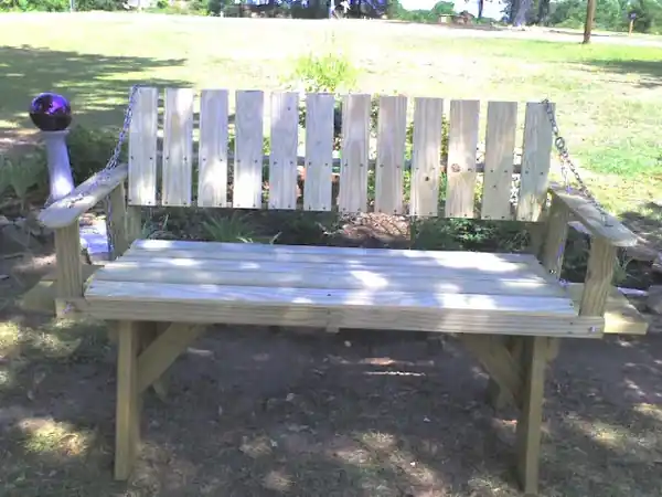 A slatted bench swing hung on chains
